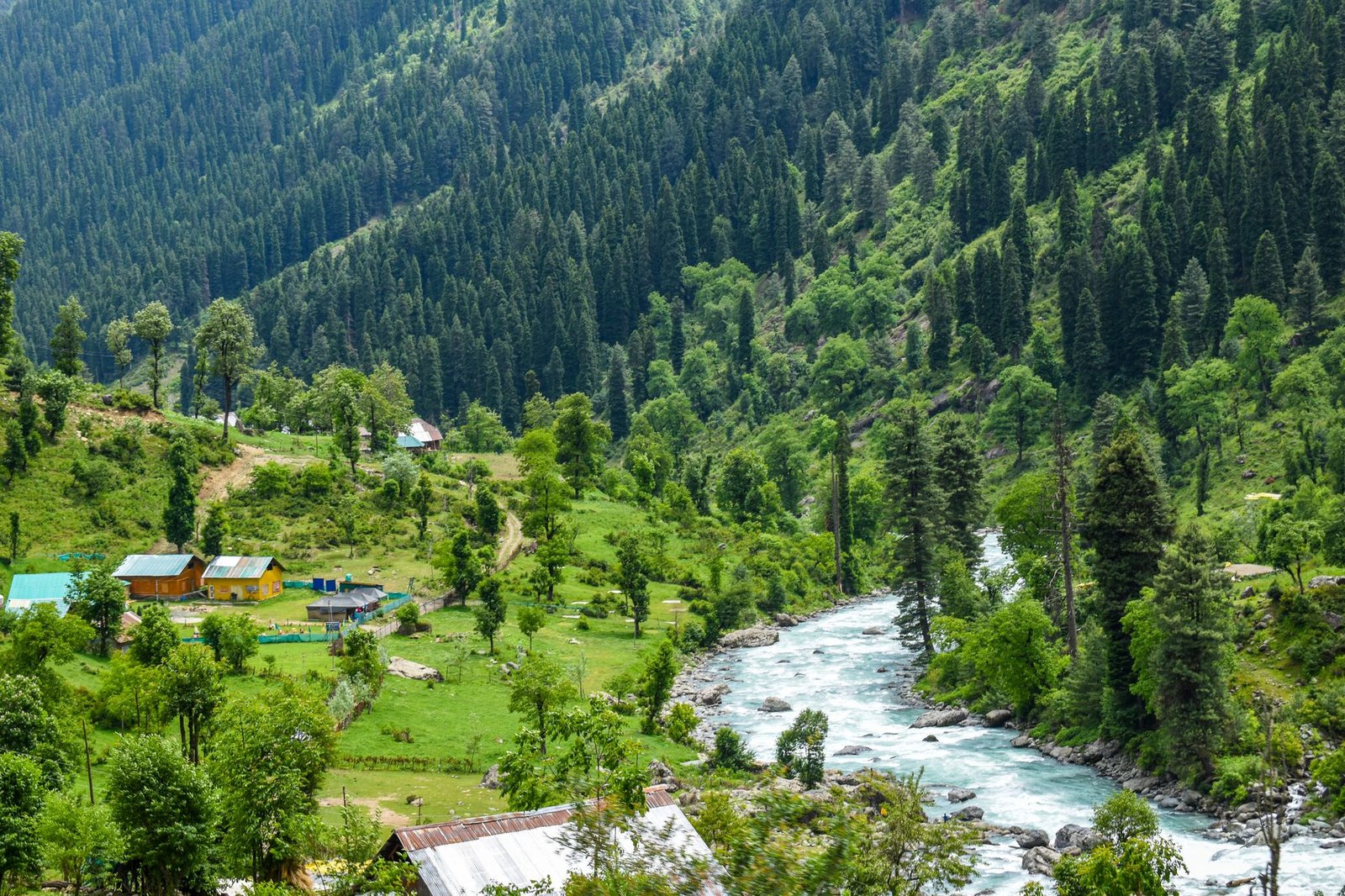 Breathtaking landscape of a river flowing through lush green valleys in Kashmir, India.