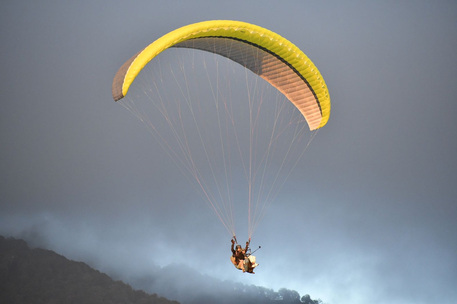 Experience the thrill of paragliding over the mist-shrouded hills of Bir, Himachal Pradesh, India.