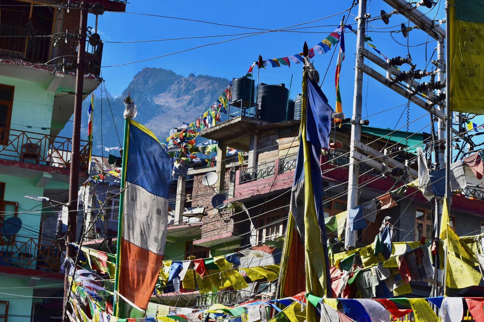 Vibrant urban landscape with Tibetan prayer flags and mountains in Manali, India.
