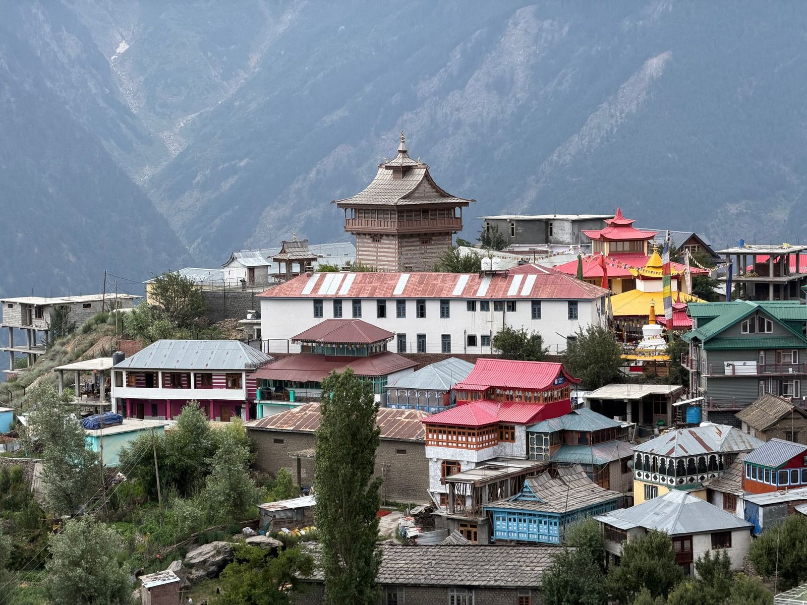 A picturesque Himalayan village with colorful rooftops and a Buddhist temple in Himachal Pradesh, India.