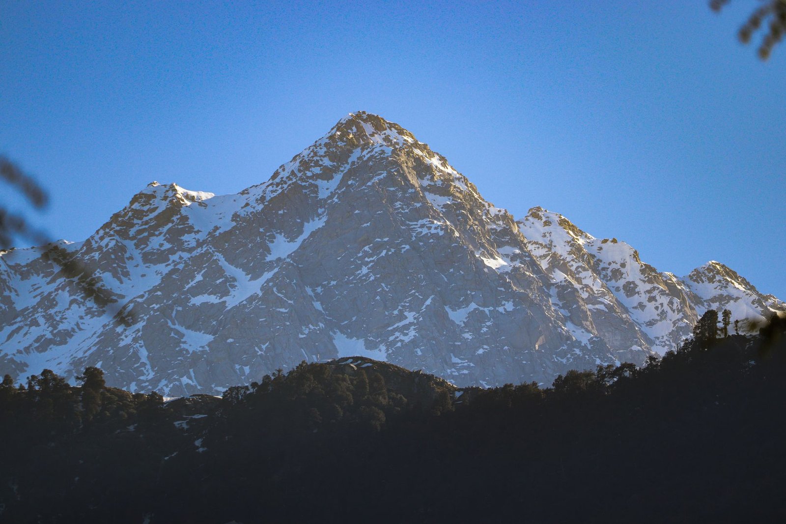 Breathtaking view of snow-covered mountains under clear blue skies in Dharamshala, India.