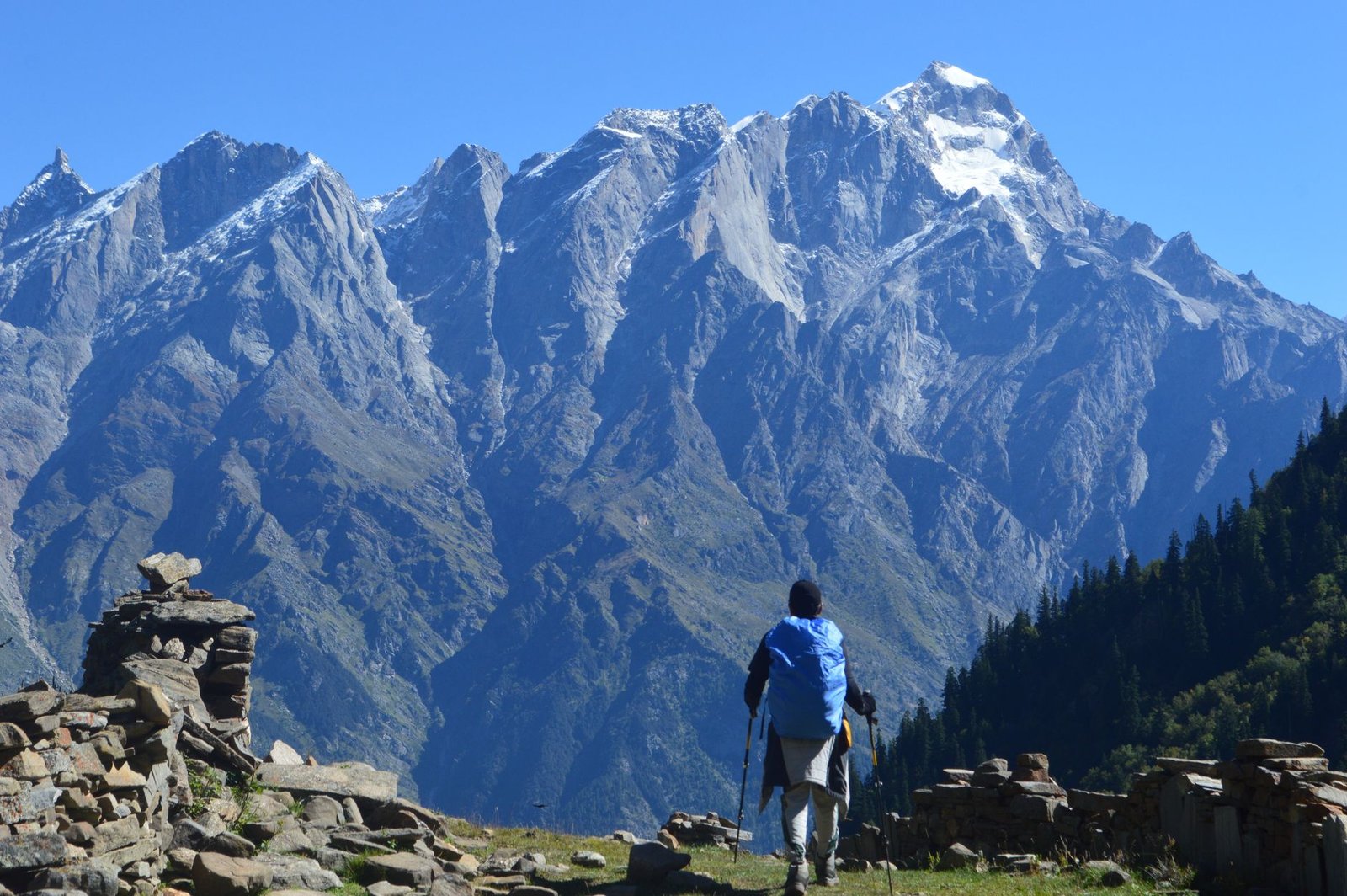 Explore the stunning Himachal Pradesh mountains with a trekker against rugged peaks under a clear blue sky.
