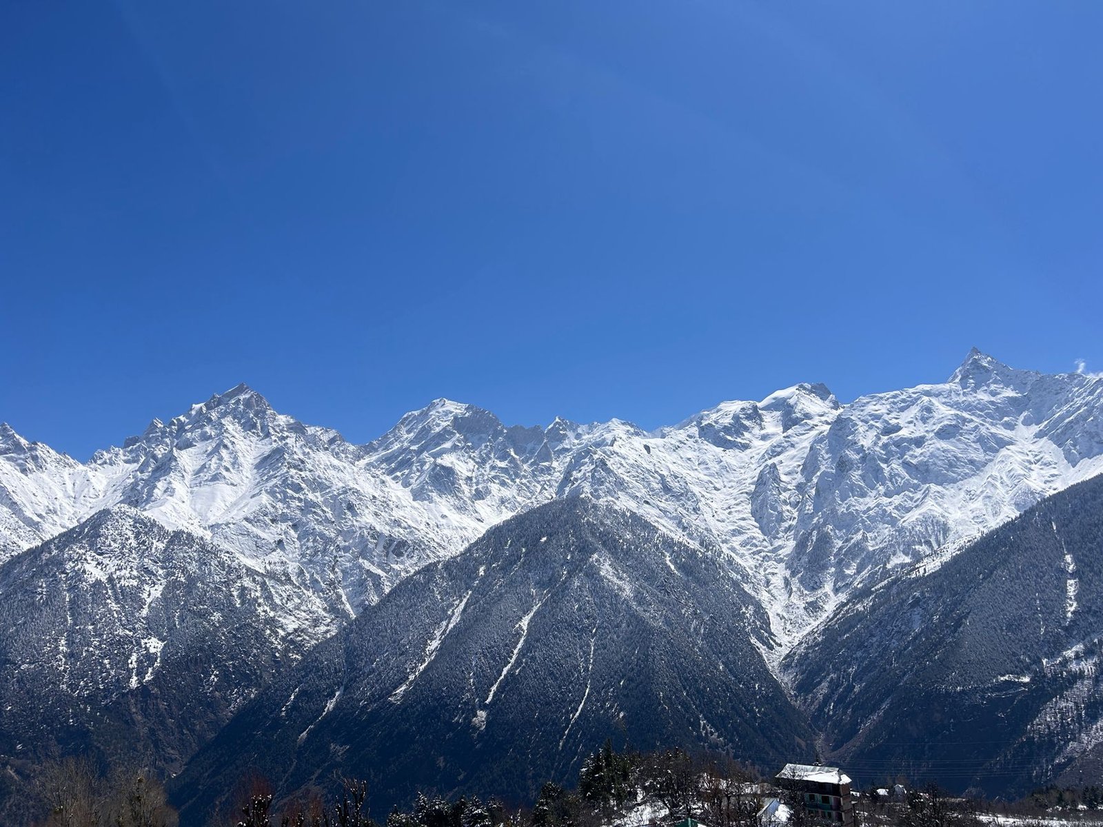 Majestic snowy mountains under a clear blue sky in Kalpa, Himachal Pradesh, India.