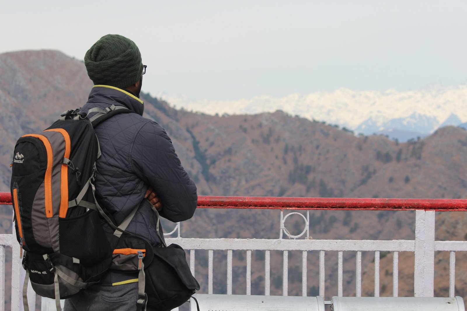 A backpacker enjoys a scenic view of the snowy mountains from Vaishno Devi.