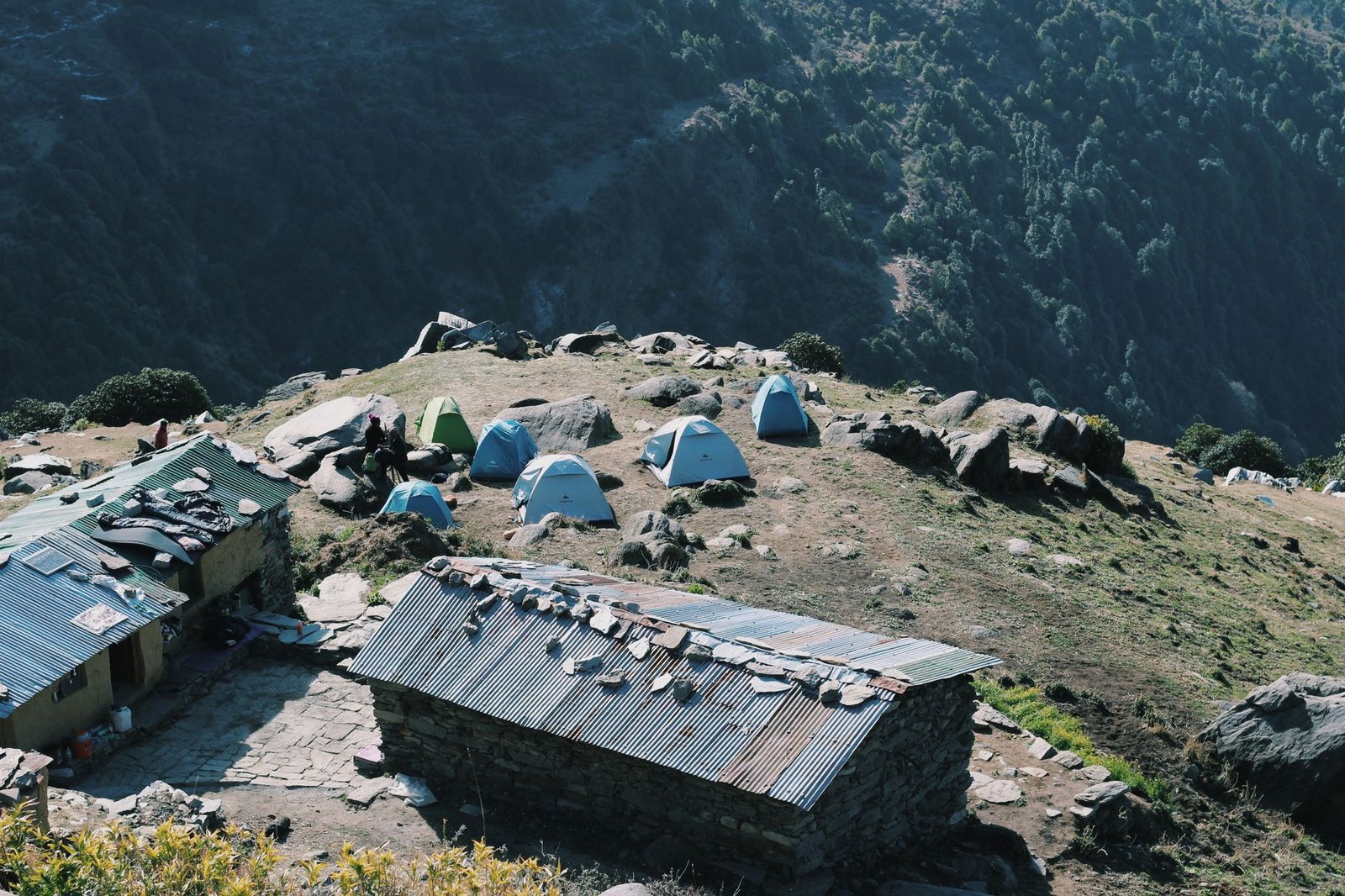 Explore a tranquil mountain campsite in Himachal Pradesh with tents and panoramic views.
