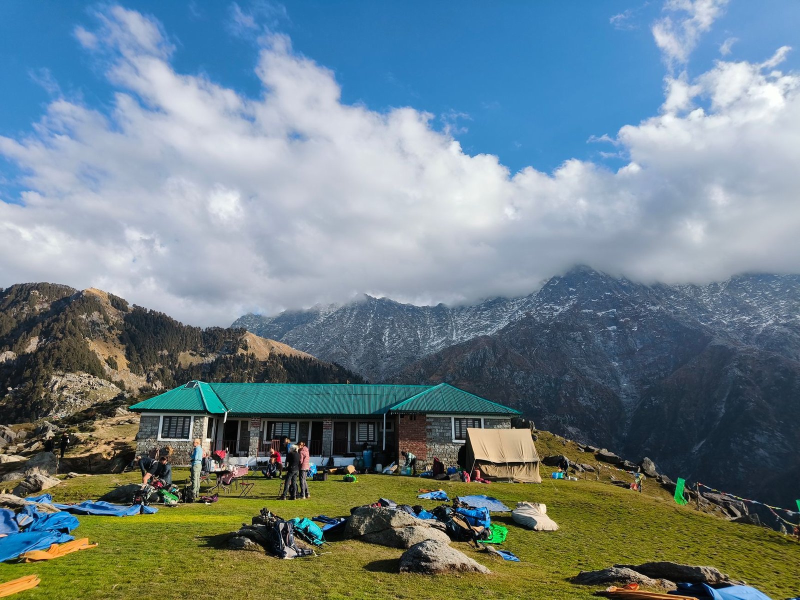 Picturesque view of a mountain lodge with tents and trekkers in Himachal Pradesh.