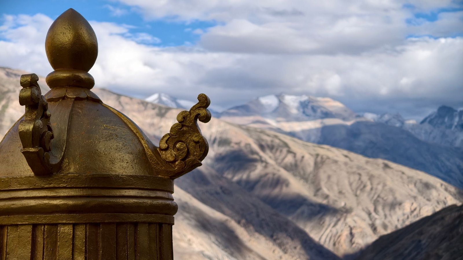 A golden ornament against a backdrop of Spiti Valley's majestic mountains in Himachal Pradesh, India.