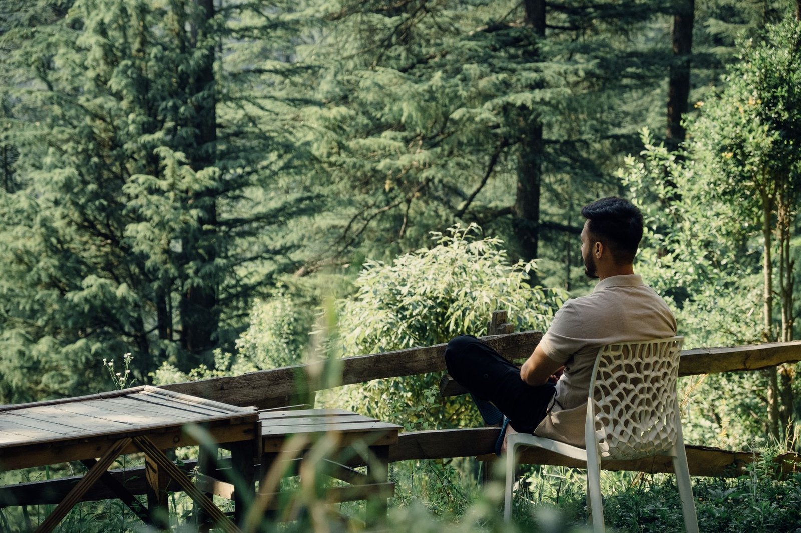 A man relaxes in a forest setting in Jibhi, HP, India, enjoying nature's tranquility.