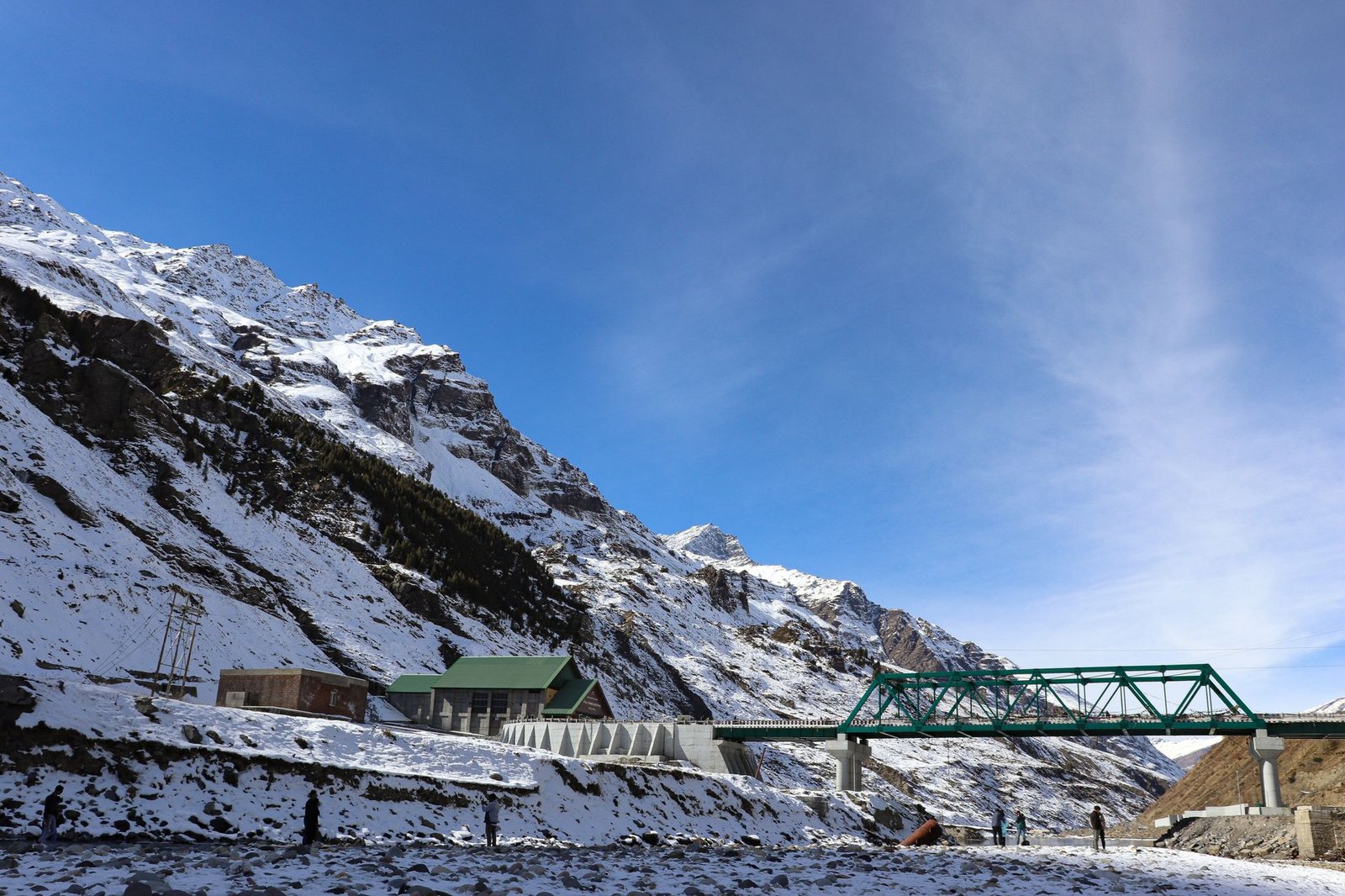 Breathtaking winter view of snowcapped mountains and bridge in Manali, India.