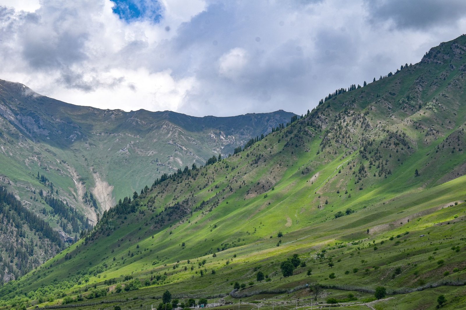 Majestic green hills under a dramatic sky in Kashmir, India.
