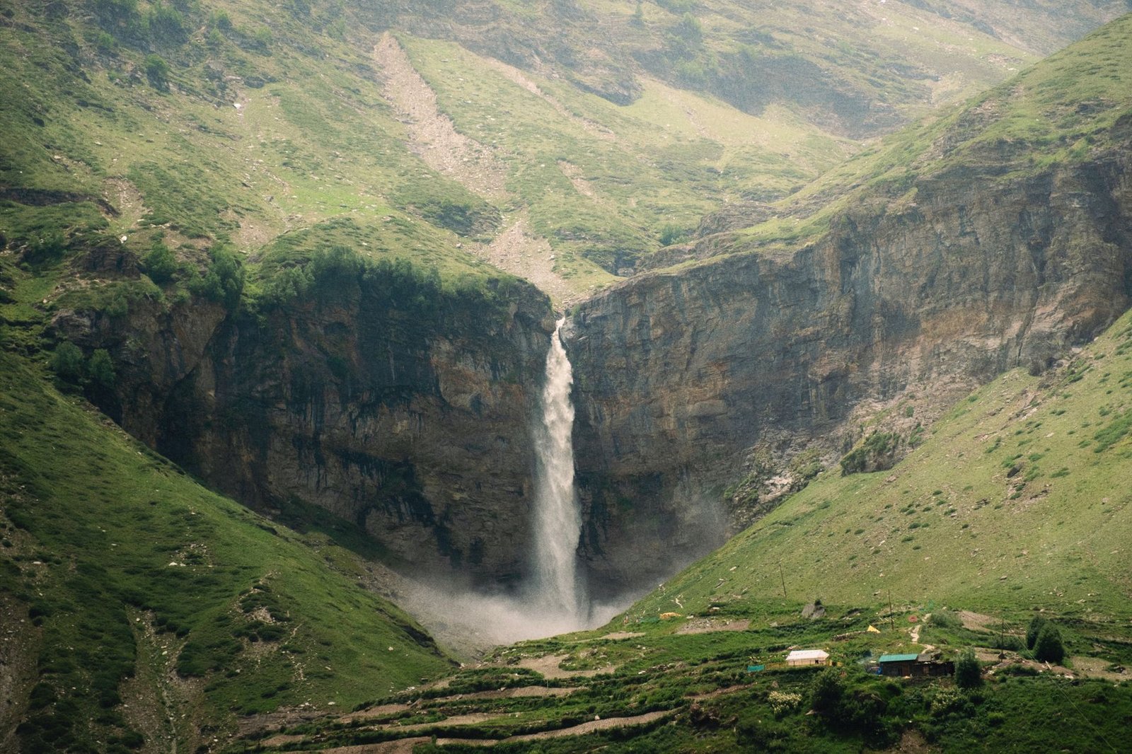 Scenic view of a stunning waterfall in Sissu, Himachal Pradesh, surrounded by the majestic Himalayas.