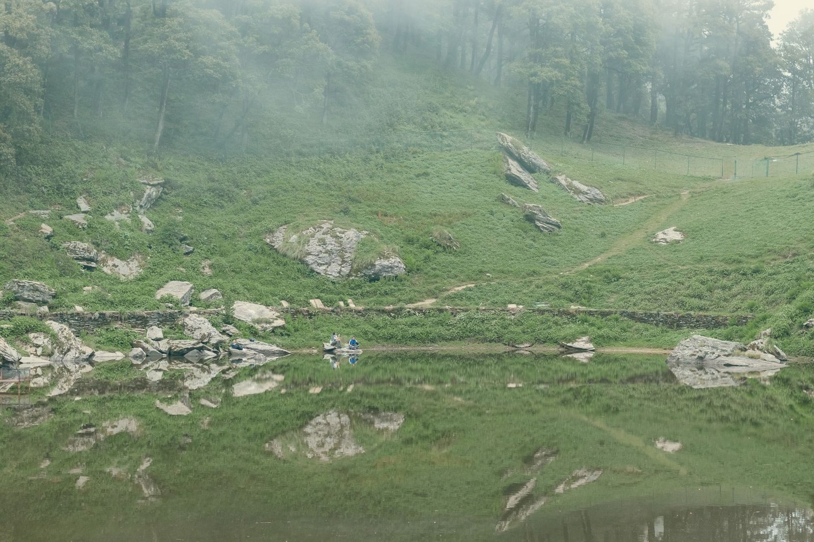 Serene mountain landscape with a reflective lake and lush greenery, perfect for adventure and nature lovers.