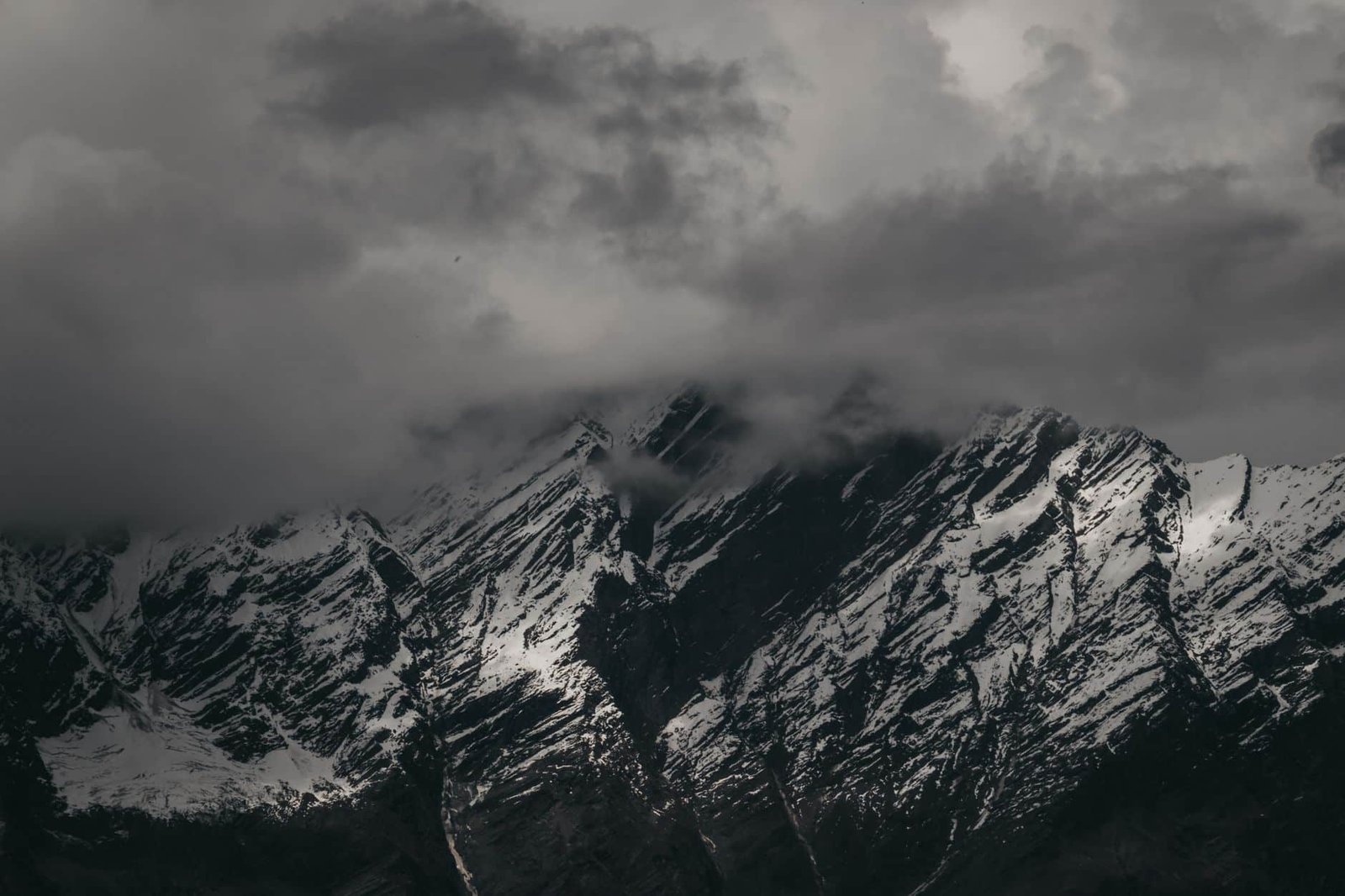 Stunning view of snow-covered mountains under a dramatic cloudy sky in Shimla, India.